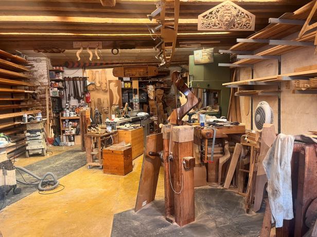 Eine Werkstatt voller Holzbearbeitungswerkzeuge und unfertiger Holzstücke.