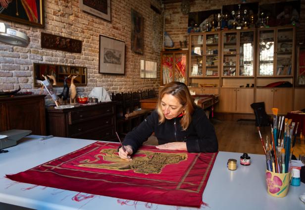 Eine Frau malt ein venezianisches Banner mit dem Markuslöwen.