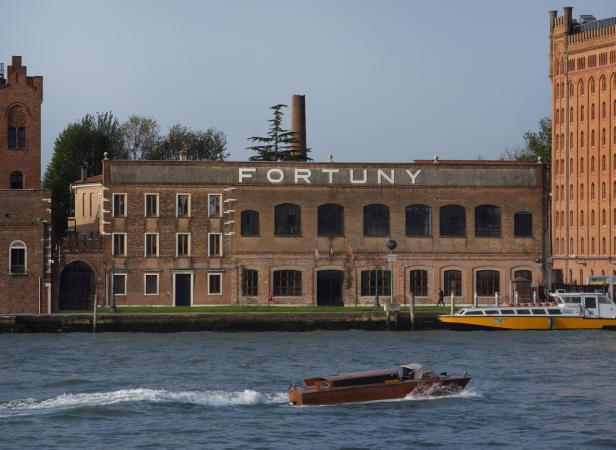 Das Fortuny-Gebäude in Venedig, gesehen vom Wasser aus, mit einem Boot im Vordergrund.