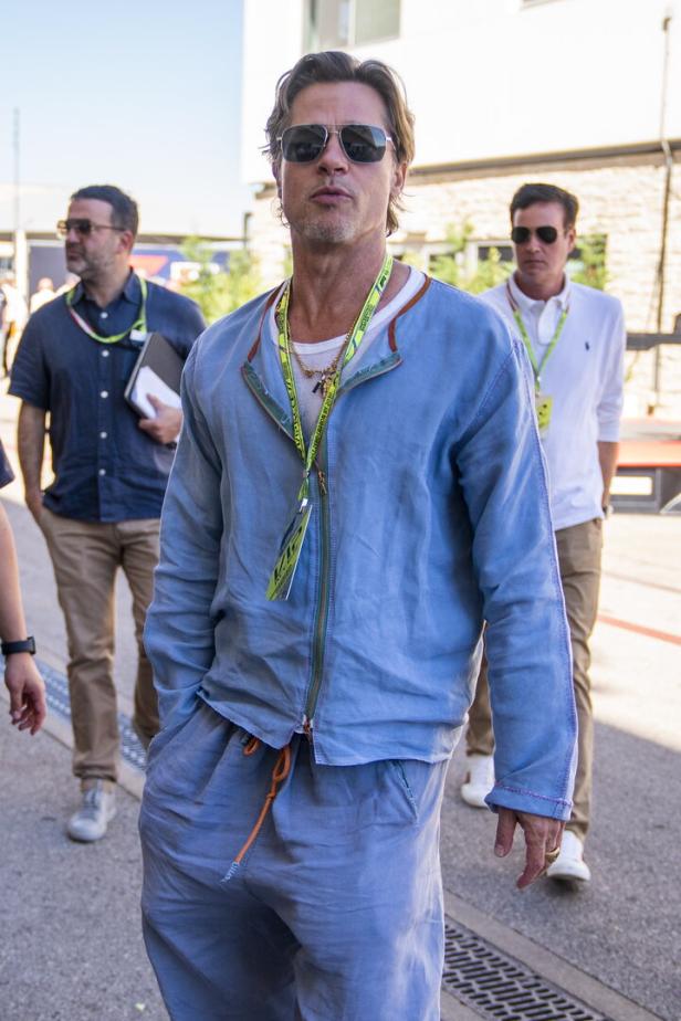 Brad Pitt trägt bei einem Formel-1-Event eine blaue Jacke und Sonnenbrille.
