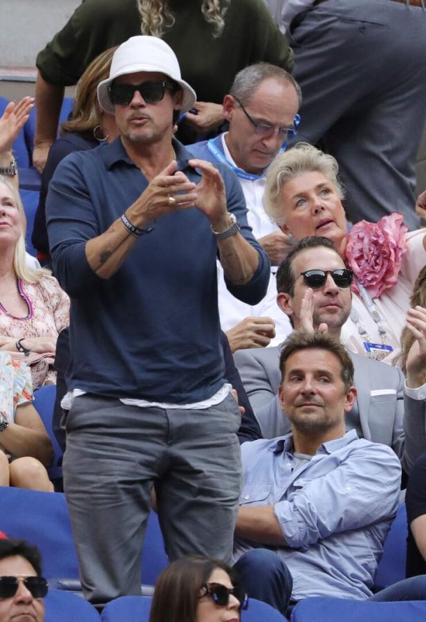 Brad Pitt und Bradley Cooper sitzen bei einem Tennismatch im Publikum.