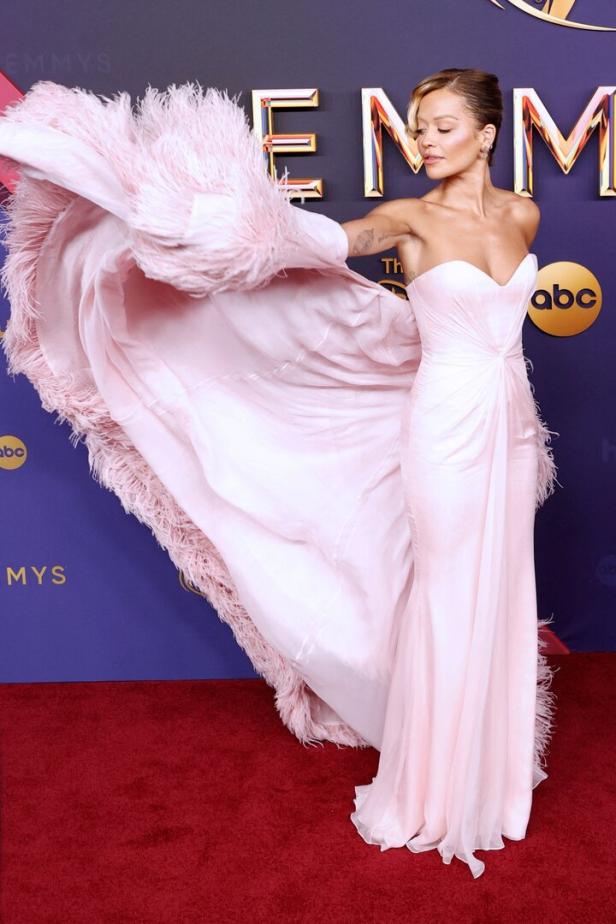 Eine Frau in einem rosa Federkleid auf dem roten Teppich der Emmys.