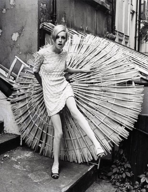 Twiggy posiert vor einem großen, runden Bambusobjekt in einem schwarz-weißen Modefoto.