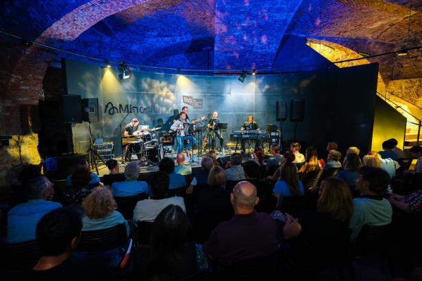 Eine Band spielt vor Publikum in einem Veranstaltungsort mit Gewölbedecke.