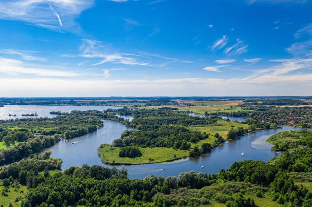 Luftaufnahme einer seenreichen Landschaft mit Wäldern und Feldern unter blauem Himmel.