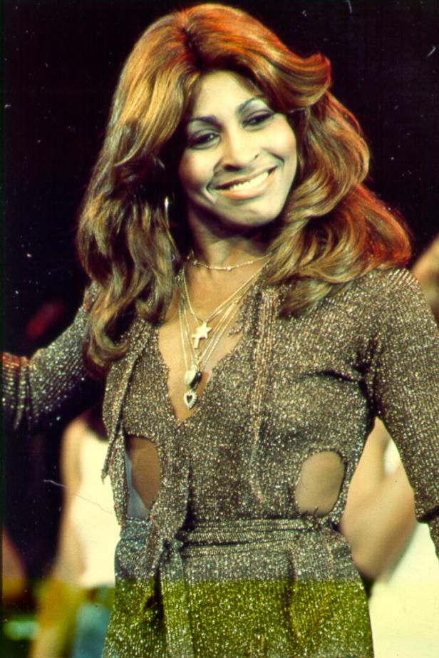 Tina Turner lächelt in einem glitzernden Kleid mit mehreren Halsketten.