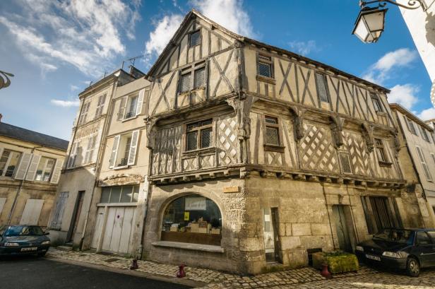 Ein sehr altes Fachwerkhaus mit Kalkstein-Elementen an einer Straßenecke in der Stadt Cognac.