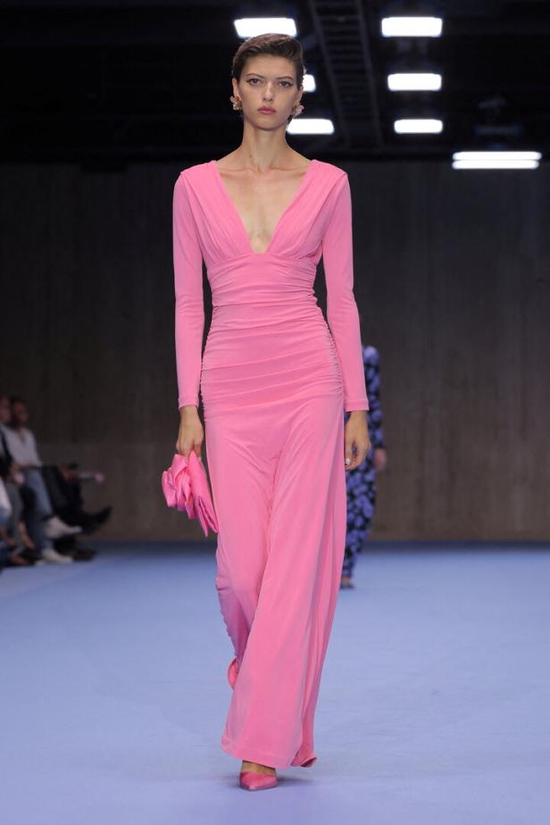 Eine Frau in einem langen, pinkfarbenen Kleid auf einem Laufsteg.