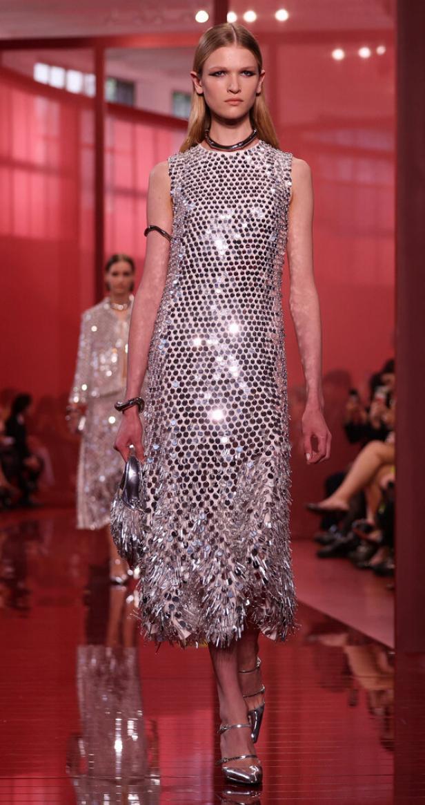 Ein Model präsentiert ein silbernes Paillettenkleid auf dem Laufsteg.