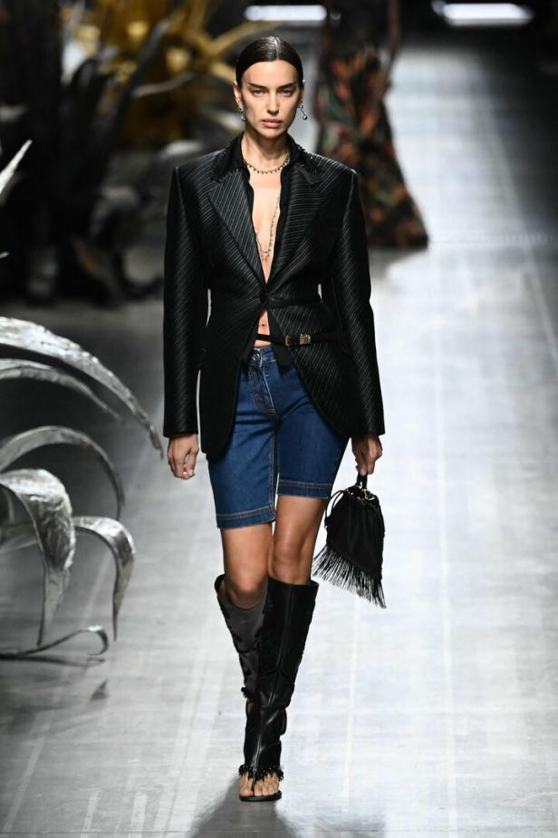 Irina Shayk auf dem Laufsteg in einem Blazer, Jeansshorts und Stiefeln.