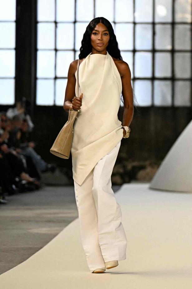 Naomi Campbell läuft in einem weißen Hosenanzug über den Laufsteg.