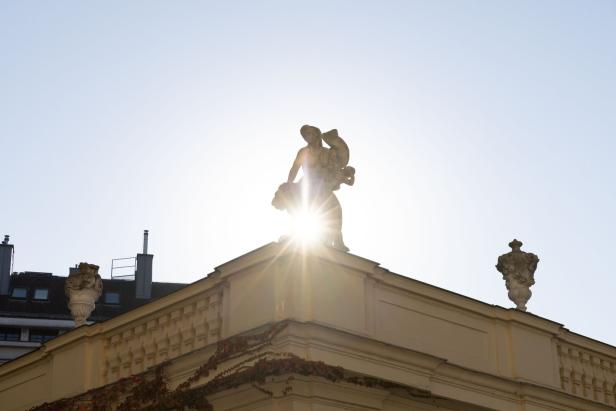 Eine Statue auf einem Gebäude wird von der Sonne angestrahlt.