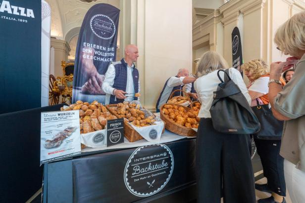 Ein Stand der Interspar-Backstube mit Körben voller Gebäck und Kunden.