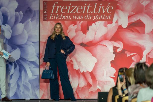 Eine Frau posiert vor einem Hintergrund mit Blumenmuster für „freizeit.live“.