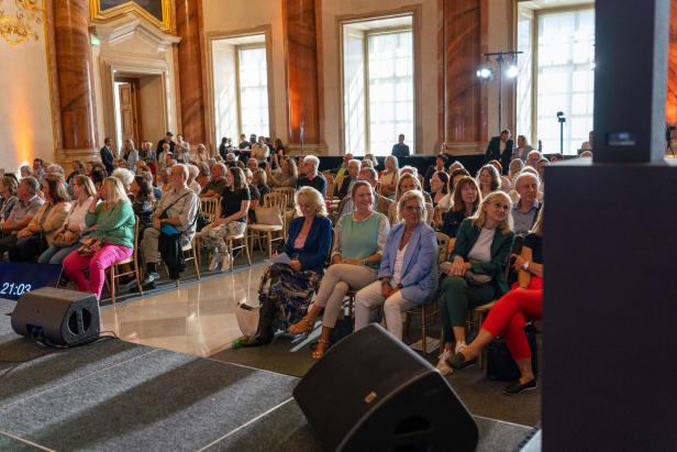 Ein Publikum sitzt in einem Saal und schaut auf eine Bühne.