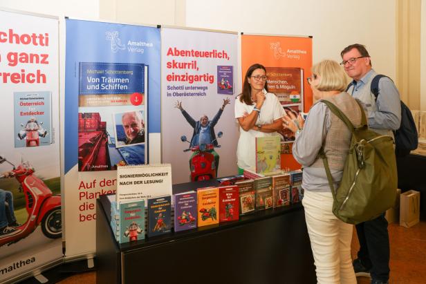 Ein Stand des Amalthea Verlags mit Büchern von Michael Schottenberg und Besuchern.