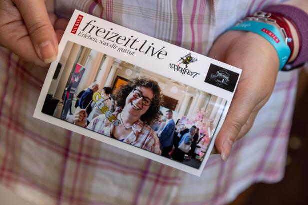 Eine Person hält eine Karte mit einem Foto vom „Stichfest“-Event.