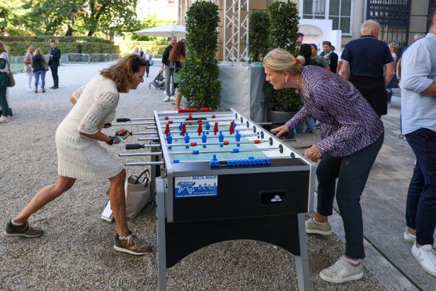 Zwei Frauen spielen Tischfußball im Freien.