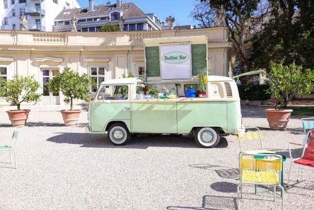 Ein Bullini Bar-Cocktailwagen in einem Park mit Tischen und Stühlen.