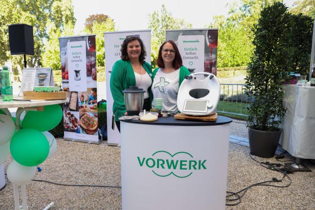 Zwei Frauen stehen an einem Vorwerk-Stand mit Thermomix-Geräten.