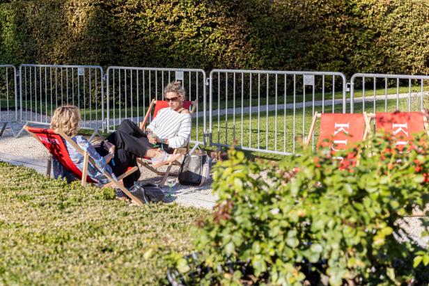 Zwei Frauen entspannen in Liegestühlen im Freien und genießen ihre Getränke.