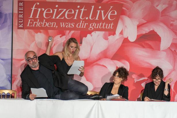 Eine Gruppe von Personen sitzt an einem Tisch vor einem Banner von freizeit.live.