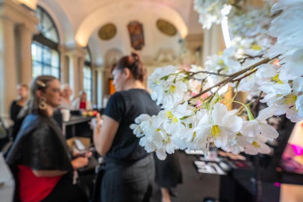 Frauen bereiten sich hinter blühenden Zweigen auf ein Event vor.