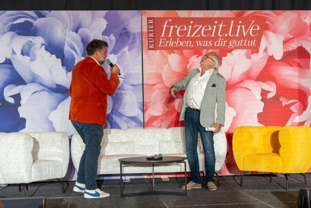 Zwei Männer stehen auf einer Bühne vor einem „freizeit.live“-Banner.