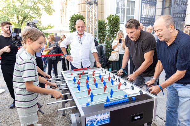 Menschen spielen an einem Tischfußballspiel im Freien.