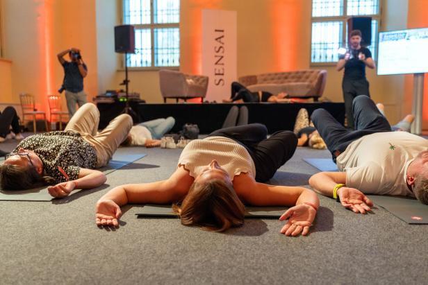 Mehrere Personen liegen entspannt auf Yogamatten während einer „Sensai“-Veranstaltung.