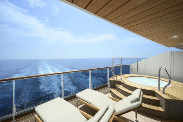 Ein Balkon auf einem Kreuzfahrtschiff mit Liegestühlen und einem Whirlpool mit Blick auf das Meer.