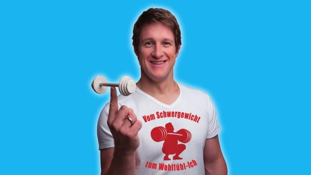 Das Steiner Prinzip von Matthias Steiner… Ein lächelnder Mann balanciert eine Mini-Hantel auf seinem Finger und trägt ein T-Shirt mit Gewichtsverlust-Motiv.