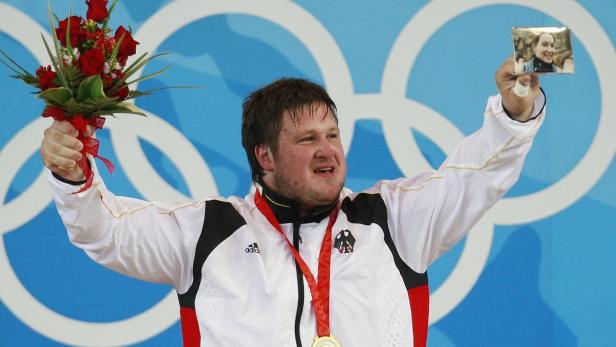 ARCHIVBILD: GEWICHTHEBEN / MATTHIAS STEINER Matthias Steiner feiert seinen Olympiasieg im Gewichtheben mit einem Foto seiner Frau und einem Blumenstrauß.