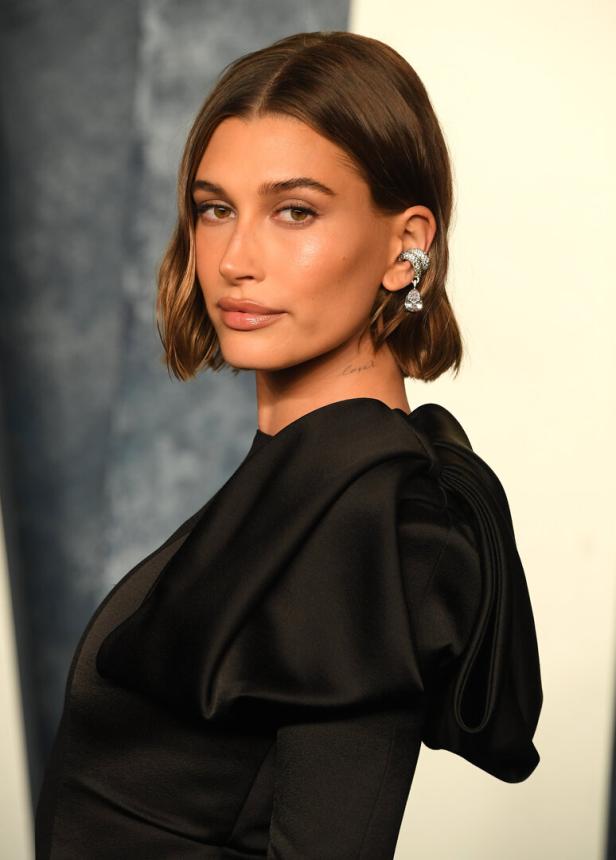 Hailey Bieber trägt ein schwarzes Kleid und einen Ohrschmuck.