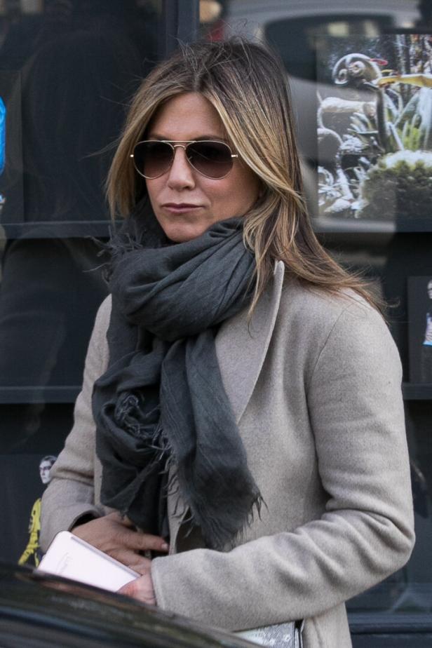 Jennifer Aniston trägt eine Sonnenbrille, einen Schal und einen Mantel.
