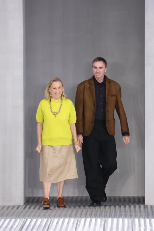 Miuccia Prada und Raf Simons laufen gemeinsam über den Laufsteg.