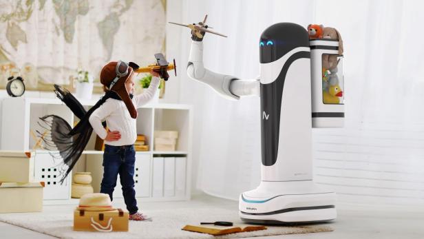 Ein Kind im Fliegerkostüm spielt mit einem Spielzeugflugzeug, das ihm ein Roboter reicht.