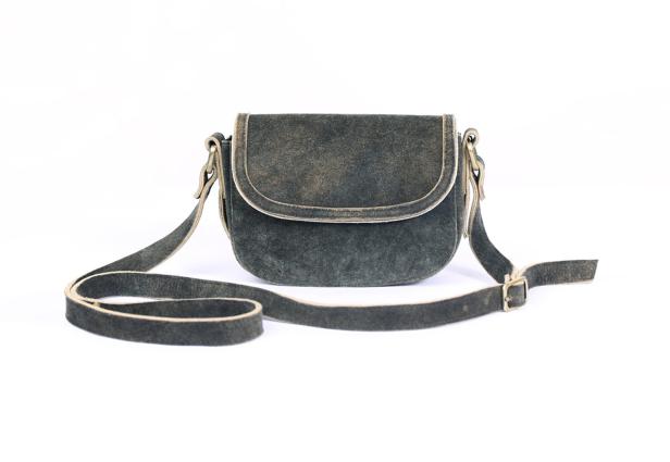 Eine graue Wildledertasche mit einem langen Riemen liegt auf einem weißen Hintergrund.