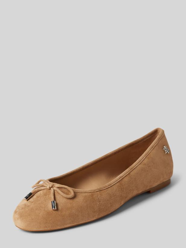 Ein beiger Wildleder-Ballerina-Schuh mit einer kleinen Schleife vorne.