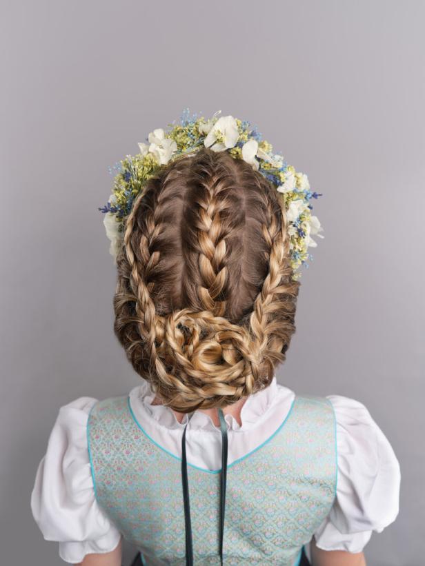 Eine Frau mit einem aufwendigen, geflochtenen Haarknoten und einem Blumenkranz im Haar.
