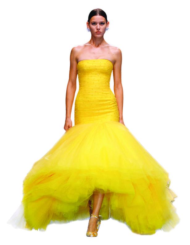Eine Frau präsentiert ein gelbes, trägerloses Abendkleid mit voluminösem Tüllrock.