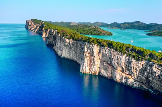 Eine lange, steile Klippe erstreckt sich ins tiefblaue Meer.