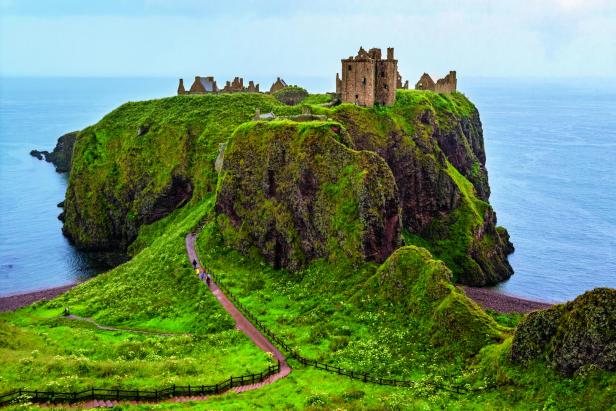 Die Ruine des Dunnottar Castle thront auf einer grünen Klippe an der Küste Schottlands.