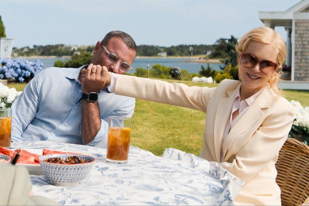 Naomi Watts und Liev Schreiber sitzen an einem Tisch im Freien; sie hält seine Hand.