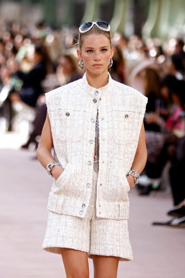 Ein Model präsentiert ein ärmelloses Tweed-Jackett und passende Shorts auf einem Laufsteg.