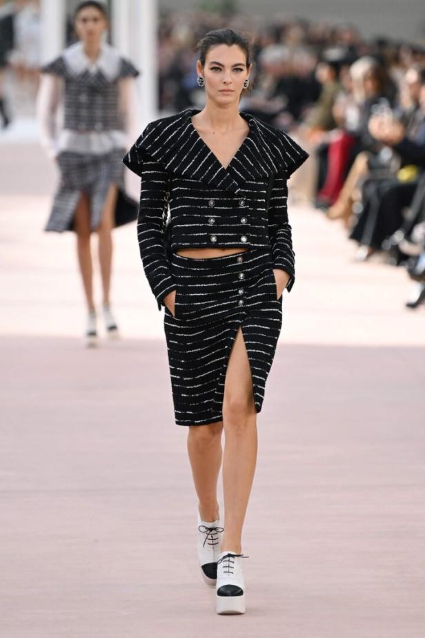 Eine Frau in einem schwarz-weiß gestreiften Chanel-Kostüm auf einem Laufsteg.