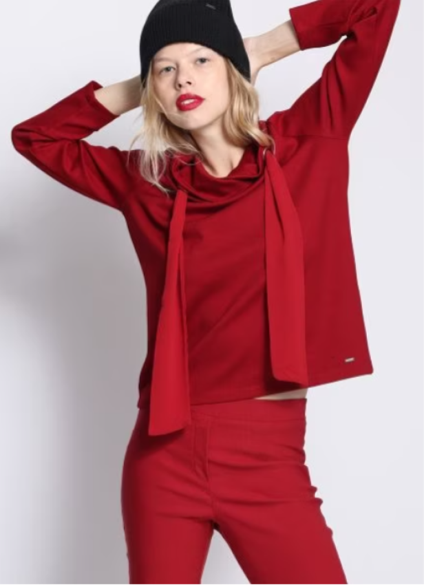 Eine Frau mit rotem Lippenstift trägt ein rotes Outfit und eine schwarze Mütze.