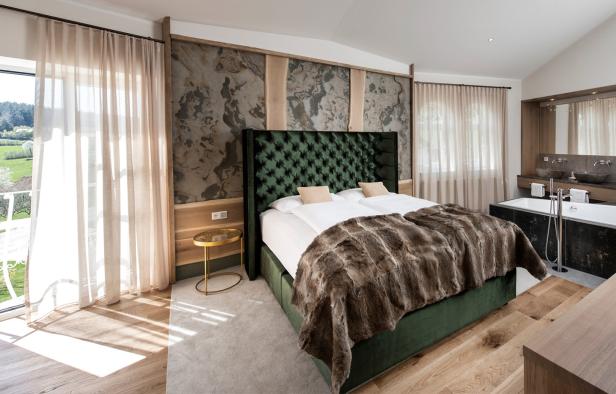 Ein Schlafzimmer mit einem grünen Bett und einem Badezimmer im Hintergrund.