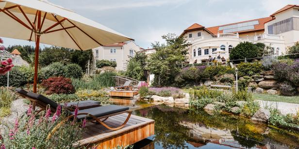 Ein Resort mit einem Teich, Liegestühlen und üppiger Vegetation.