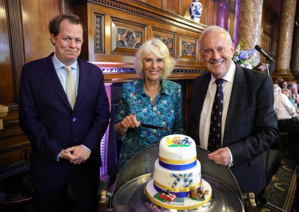 Königin Camilla schneidet mit zwei Herren eine Geburtstagstorte anlässlich ihres 75. Geburtstages an.
